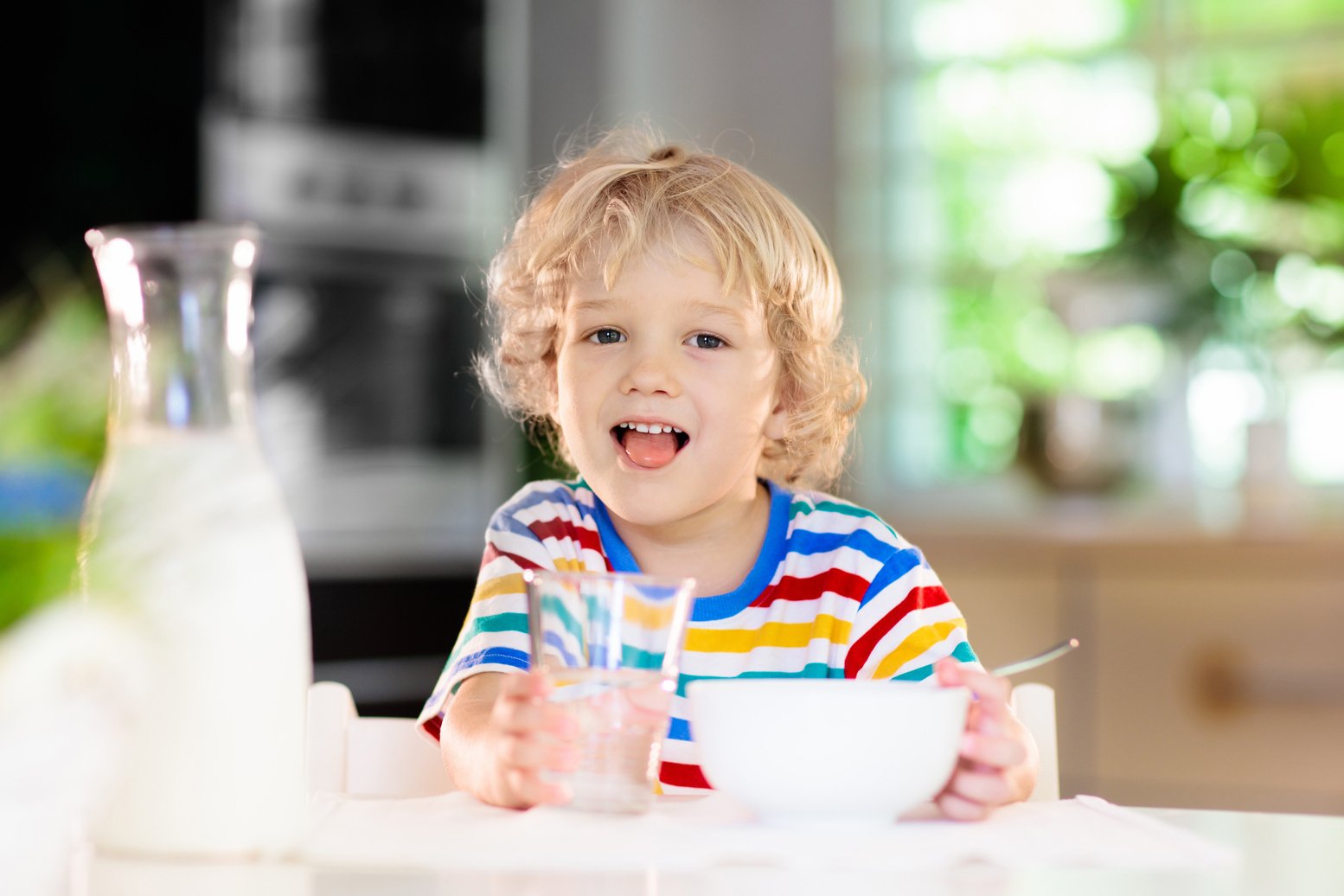 Child eating breakfast. Kid with milk and cereal.